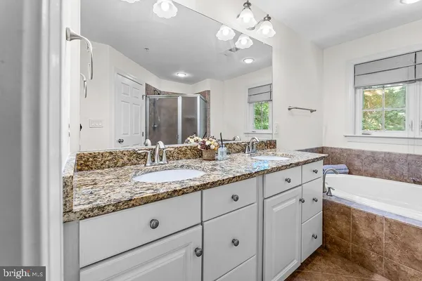 a bathroom with a granite countertop bathtub a double vanity sink a vanity and a large mirror
