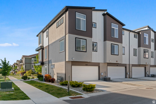 8307 Durham Street Sandy, UT 84070 - Photo 27 of 29 Modern townhouse exterior featuring multi-toned siding, attached garages, ample windows, and a landscaped walkway