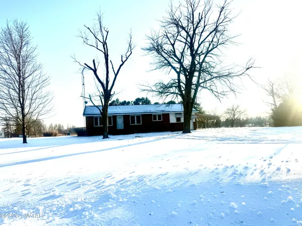 a view of a large white house with a yard covered with snow and trees