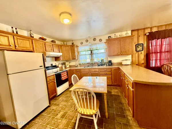 a kitchen with stainless steel appliances refrigerator stove dining table and chairs
