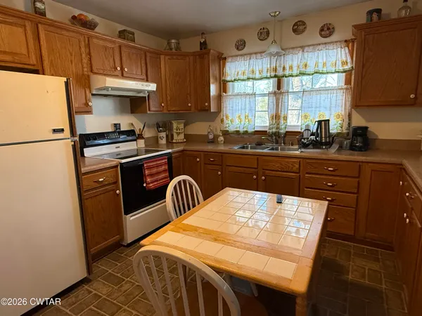 a kitchen with granite countertop a refrigerator a sink a stove and white cabinets