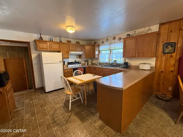 a kitchen that has a sink a table and chairs in it