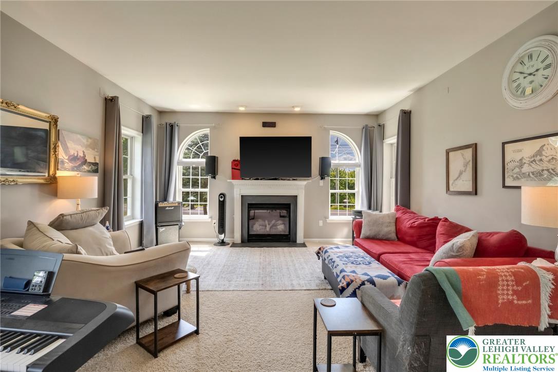 204 Bushkill Ridge Road Wind Gap, PA 18091 - Photo 16 of 48 Sun-filled living area featuring a cozy fireplace and elegant arched windows.