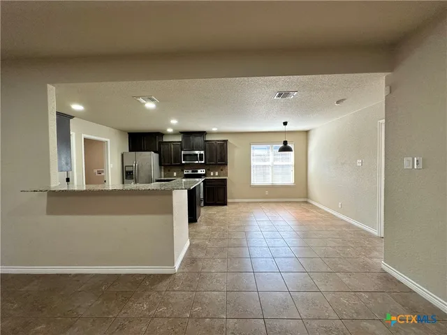 a kitchen with stainless steel appliances kitchen island granite countertop a refrigerator and a stove top oven