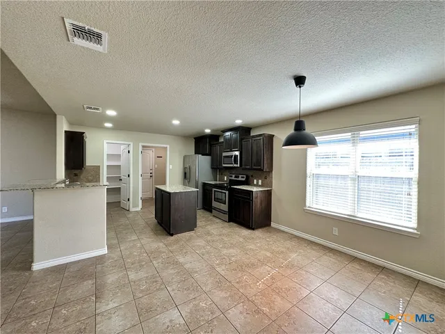 a kitchen with stainless steel appliances granite countertop a refrigerator and a stove
