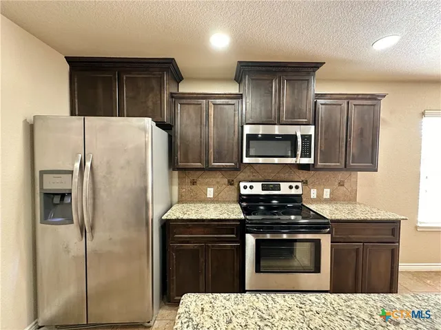 a kitchen with stainless steel appliances granite countertop a stove a sink and a refrigerator