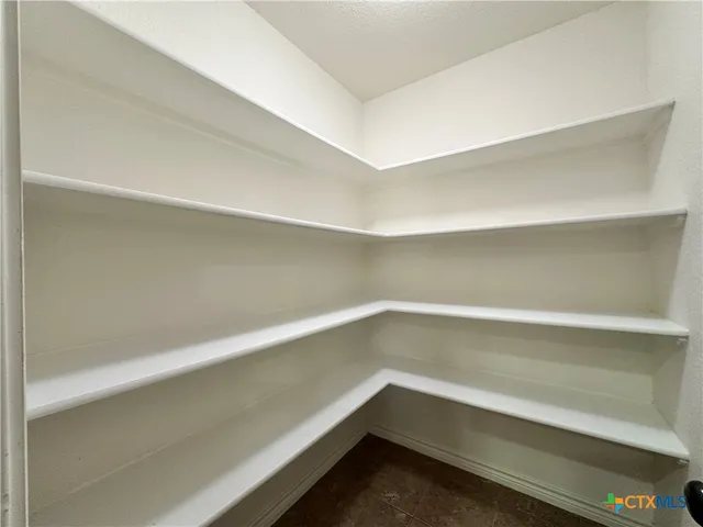 a view of an empty room and chandelier fan
