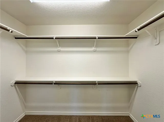an empty room with closet and a chandelier fan