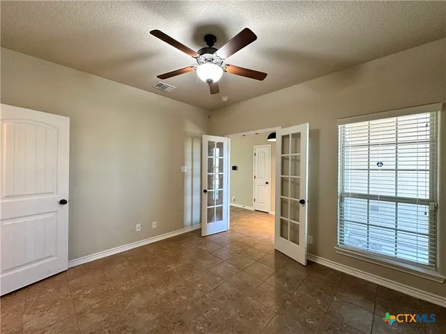 an empty room with windows and fan