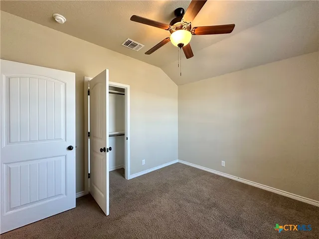 an empty room with closet and a chandelier fan