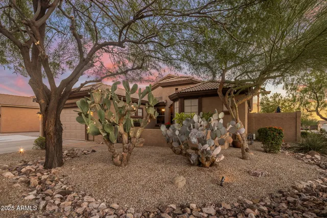 a backyard of a house with table and chairs under an large tree