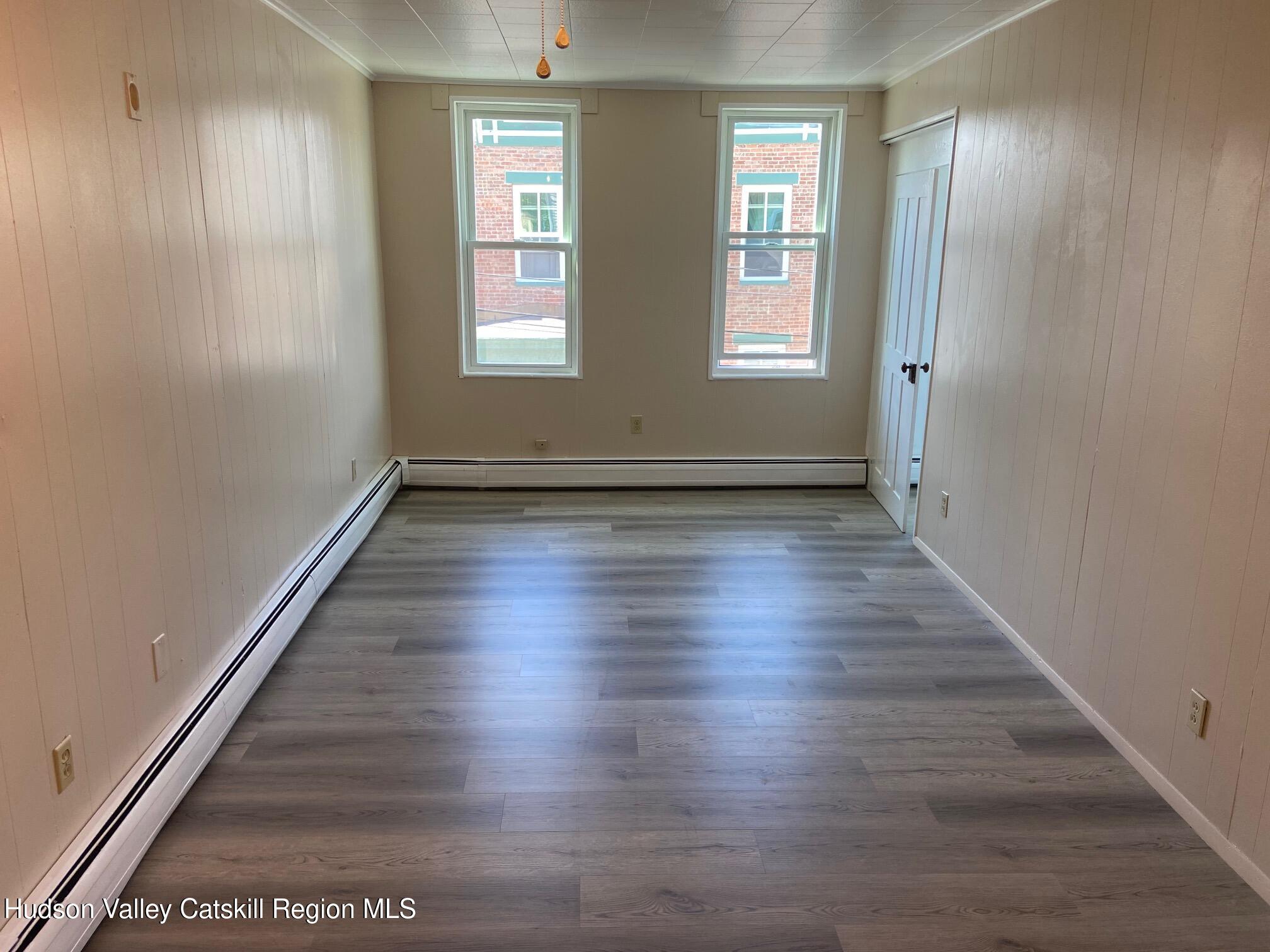 214 Robinson Street, Unit 2 Hudson, NY 12534 - Photo 6 of 13 an empty room with wooden floor and windows