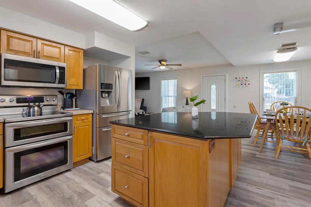 1411 Gray Street South Gulfport, FL 33707 - Photo 6 of 25 a kitchen with stainless steel appliances granite countertop a stove top oven a sink dishwasher a dining table and chairs with wooden floor