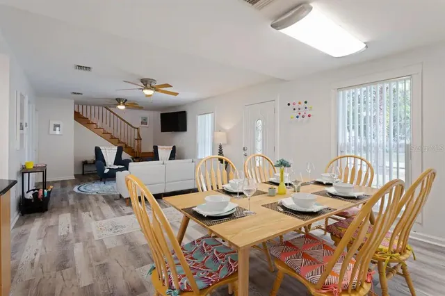 a view of a dining room and livingroom with furniture wooden floor a rug a painting and a chandelier