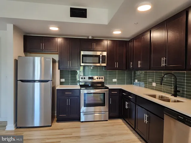 a kitchen with stainless steel appliances granite countertop a refrigerator a sink a stove and cabinets