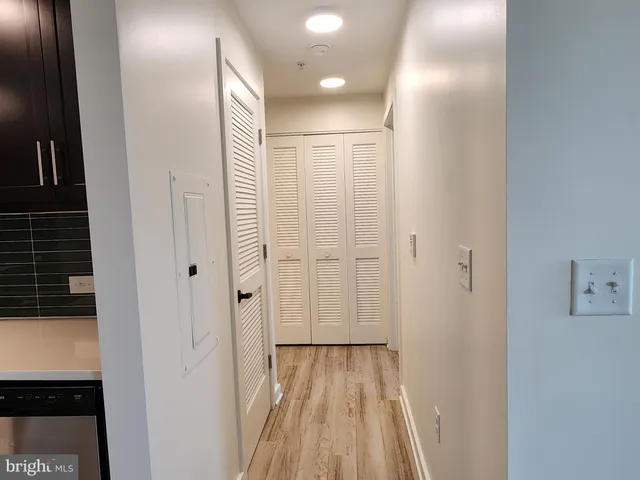 a view of a hallway with wooden floor and a bathroom
