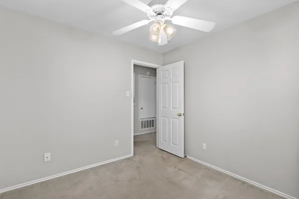 an empty room with a chandelier fan and a bathroom
