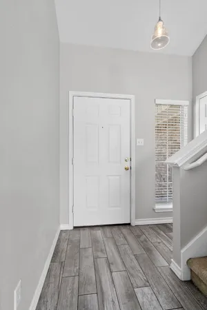 an empty room with wooden floor cabinet and windows