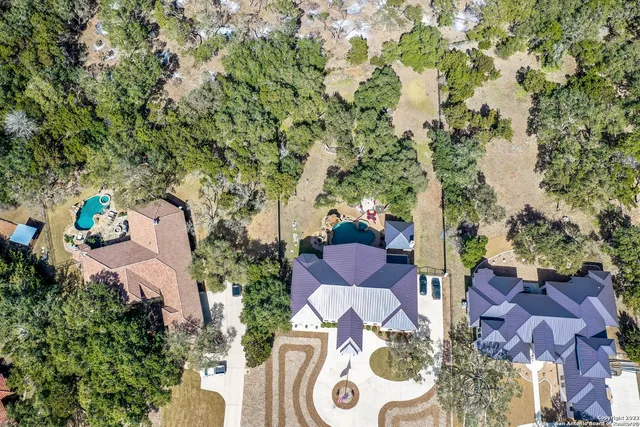 an aerial view of residential houses with outdoor space and trees all around