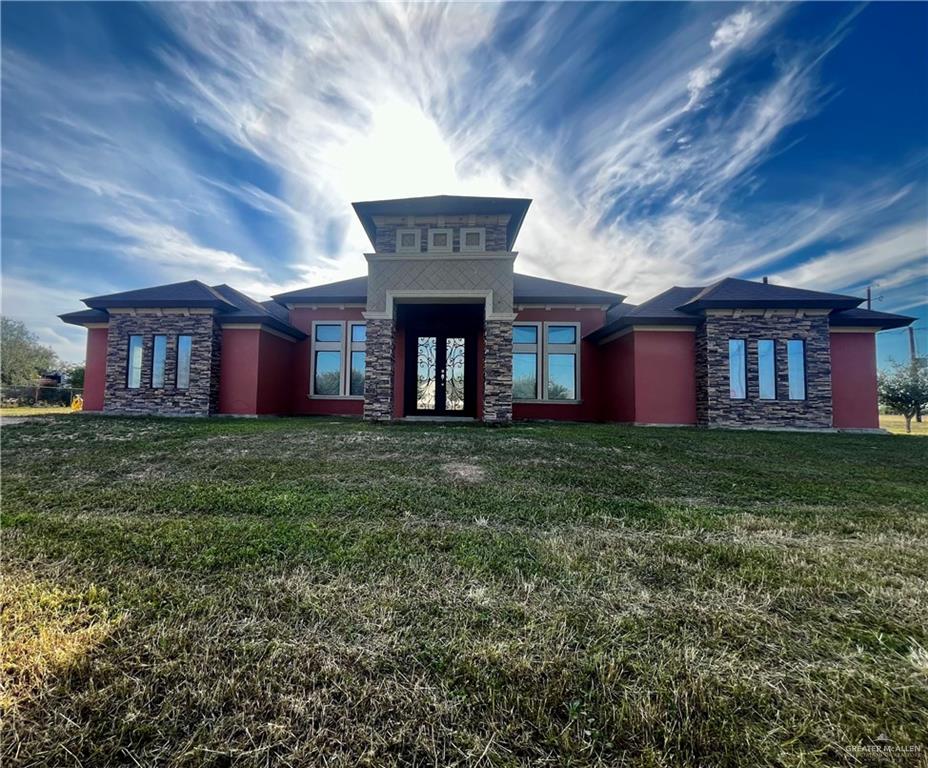 View of front facade featuring stone siding and a front lawn