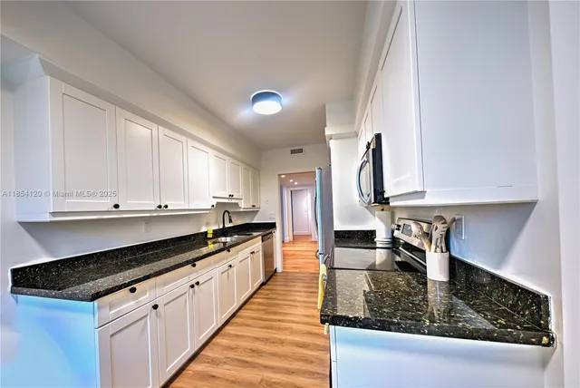 a kitchen with stainless steel appliances granite countertop a sink stove and cabinets