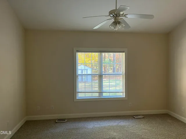 an empty room with a window and a fan