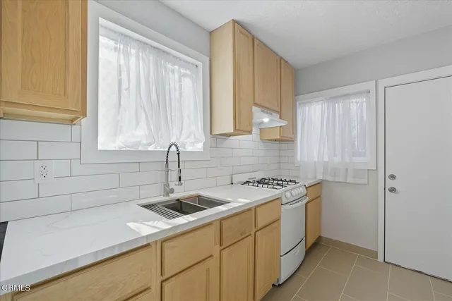 a utility room with a sink a cabinetry and a window