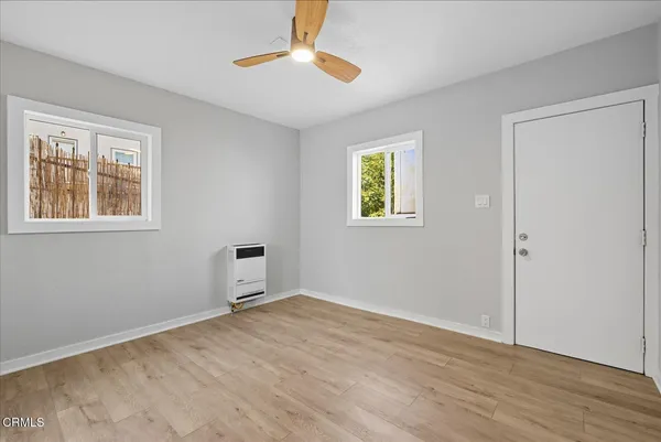 a view of empty room with wooden floor and fan
