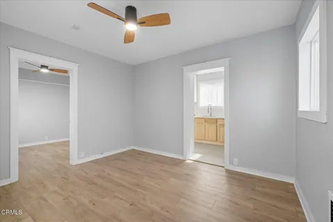 an empty room with wooden floor cabinet and windows