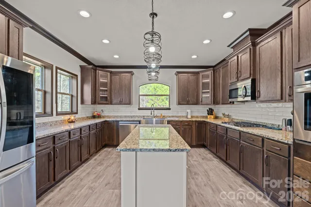 a large kitchen with stainless steel appliances granite countertop a stove and a sink