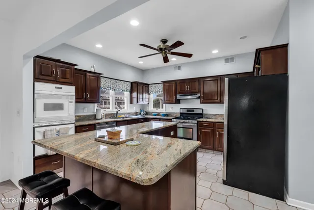 a kitchen with stainless steel appliances granite countertop a sink refrigerator and cabinets
