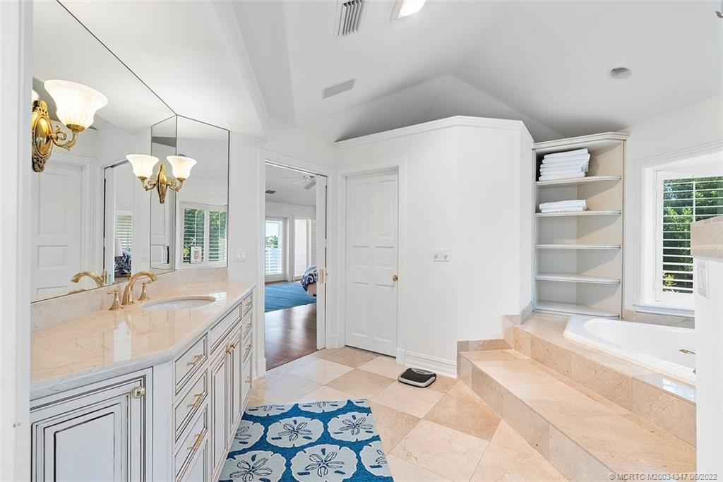 2421 Bahia Way Stuart, FL 34996 - Photo 18 of 83 a spacious bathroom with a sink a mirror a bathtub and next to a window
