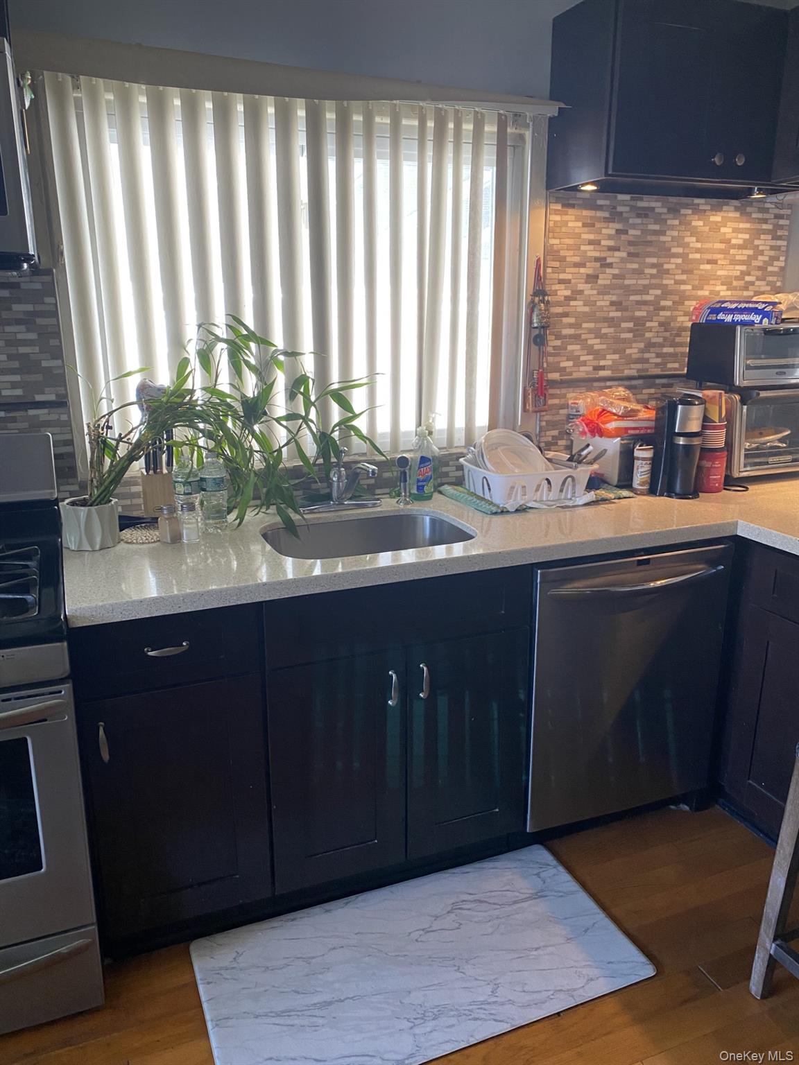 145-24 223rd Street Queens, NY 11413 - Photo 4 of 16 a kitchen with large window and wooden cabinets