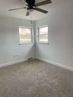 en empty room with windows and ceiling fan