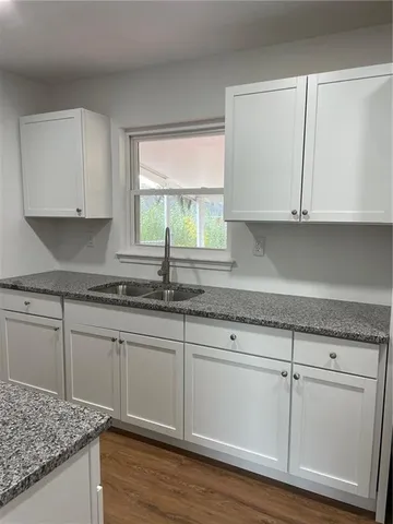 a kitchen with granite countertop white cabinets and a sink