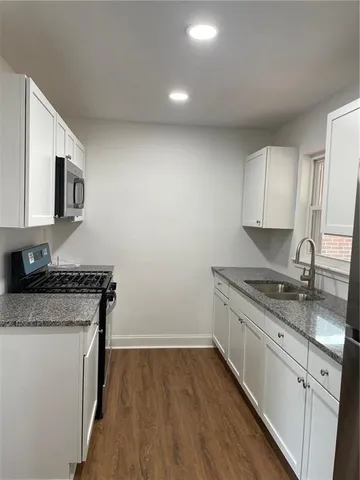 a kitchen with granite countertop a sink stove and cabinets