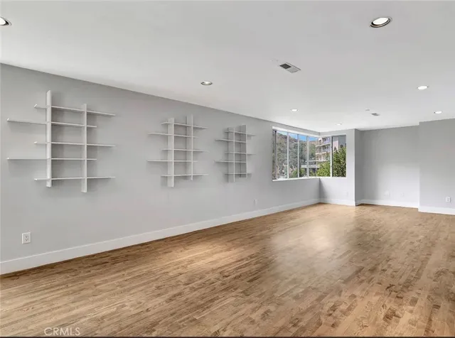 a view of an empty room with a window and wooden floor