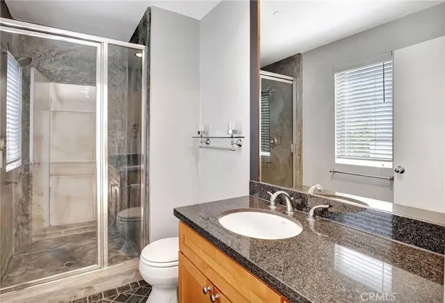 a bathroom with a granite countertop sink toilet and shower
