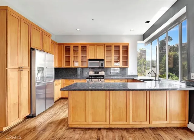a kitchen with stainless steel appliances granite countertop a refrigerator a stove and a sink with wooden floor