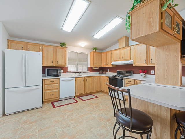 3941 West 40 North Hurricane, UT 84737 - Photo 14 of 55 Kitchen featuring wood-finish cabinetry, solid surface countertops, a white appliance suite, tile flooring, and vaulted ceilings with recessed lighting