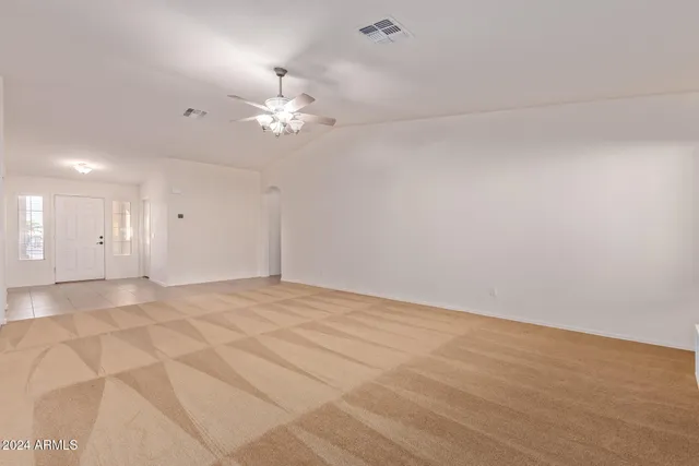 a view of an empty room with a chandelier fan