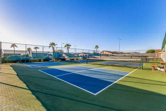 a view of a tennis ground with large trees