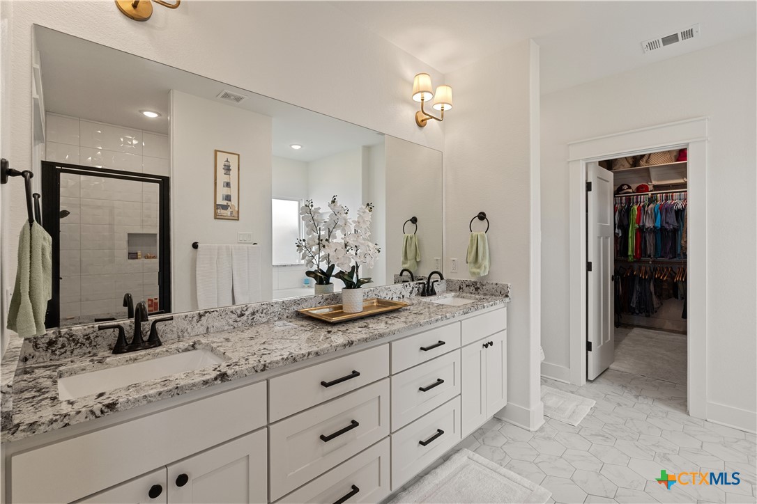 942 Inka Road Salado, TX 76571 - Photo 19 of 46 a bathroom with a granite countertop double vanity sink and a mirror