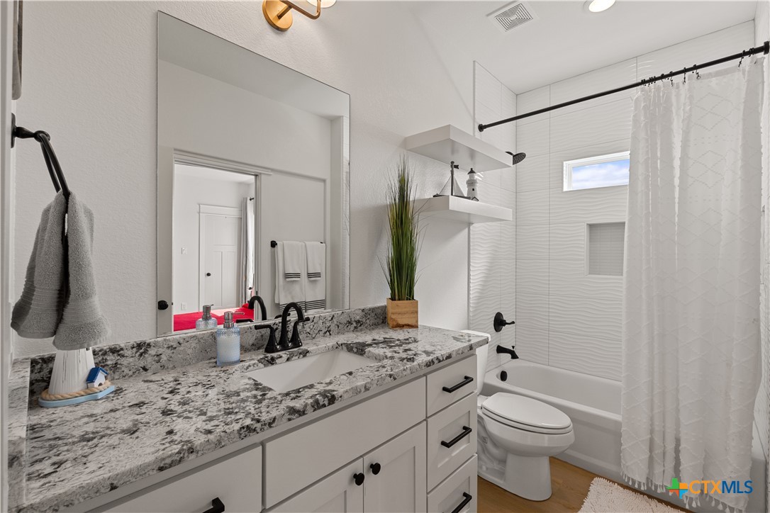 942 Inka Road Salado, TX 76571 - Photo 30 of 46 a bathroom with a granite countertop sink mirror vanity and toilet