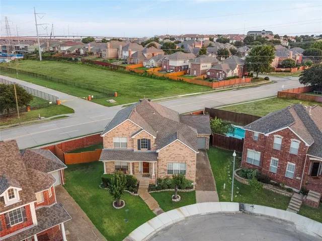 a view of a white house next to a yard with big trees