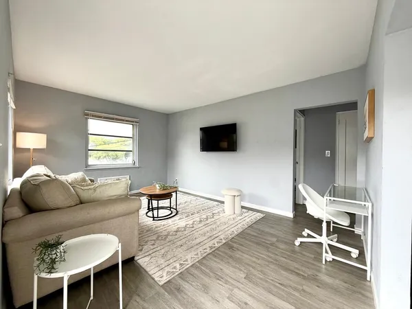 a living room with furniture a flat screen tv and wooden floor