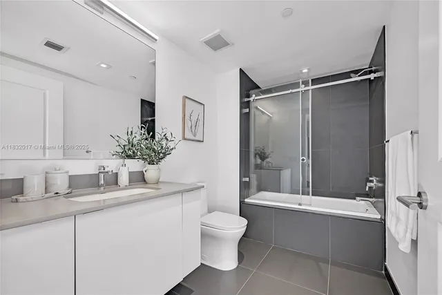 a bathroom with a granite countertop sink toilet a mirror and shower
