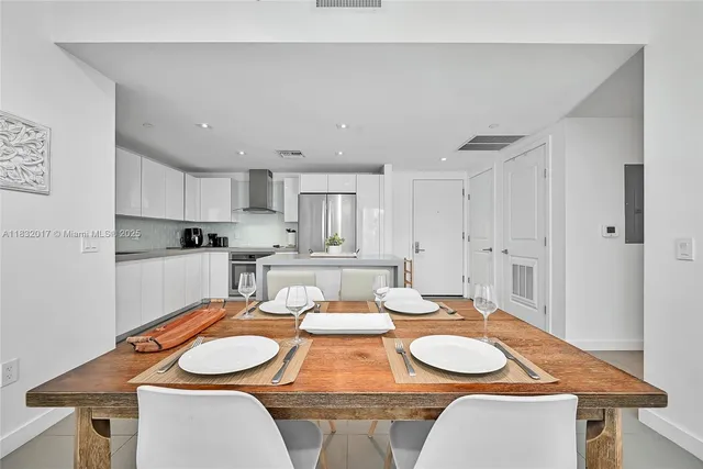 a dining room with wooden floor and white kitchen view