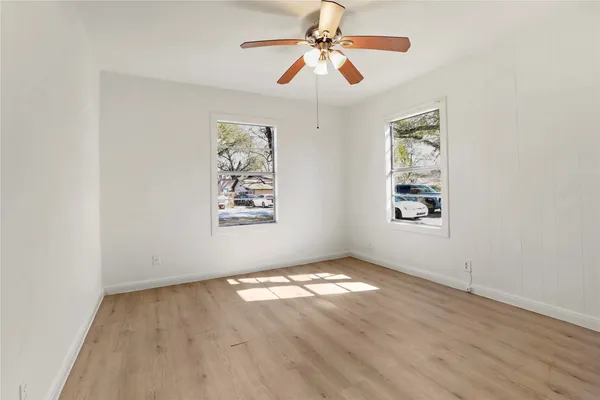 an empty room with windows and fan