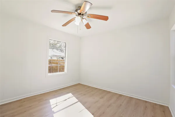 an empty room with a window and a fan